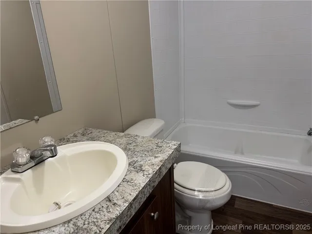 a bathroom with a granite countertop toilet a sink and bathtub