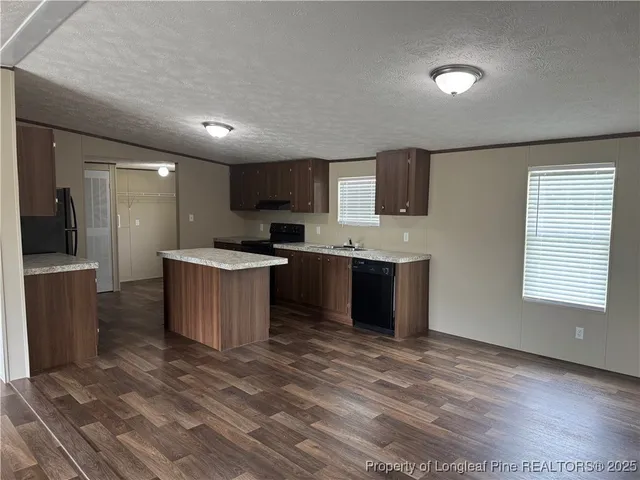a large kitchen with a large counter top a sink stainless steel appliances and cabinets