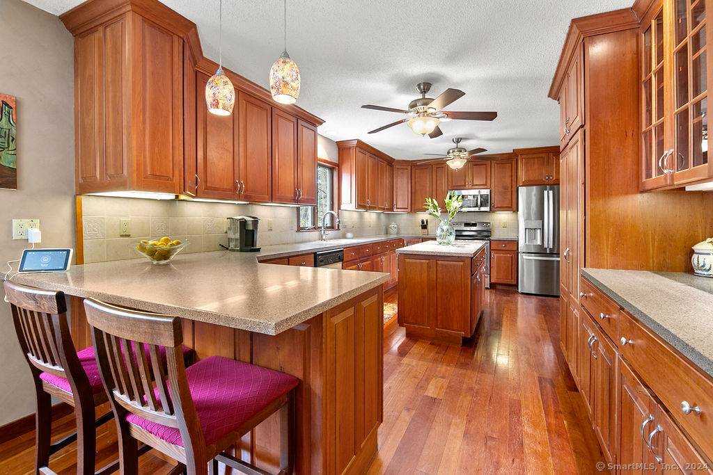 a kitchen with stainless steel appliances granite countertop a dining table chairs sink and cabinets