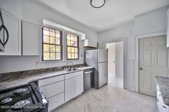 a kitchen with stainless steel appliances granite countertop a stove a sink and a refrigerator