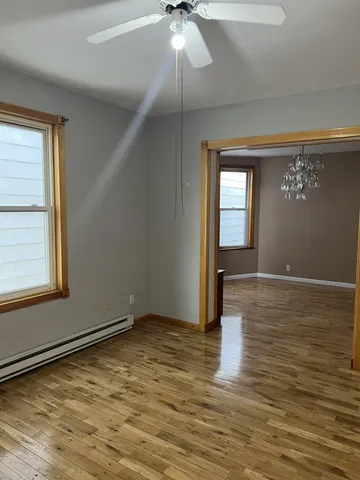 a view of an empty room with window and wooden floor