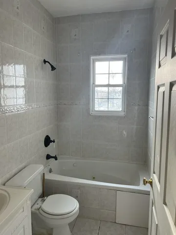 a bathroom with a toilet bathtub window and shower