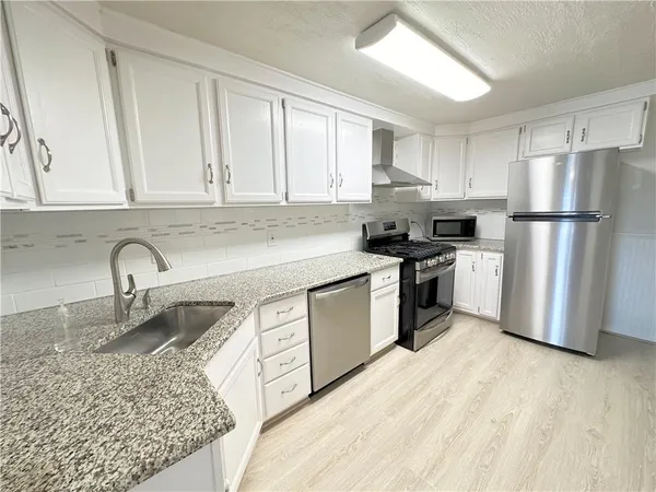a kitchen with stainless steel appliances granite countertop a refrigerator sink and cabinets