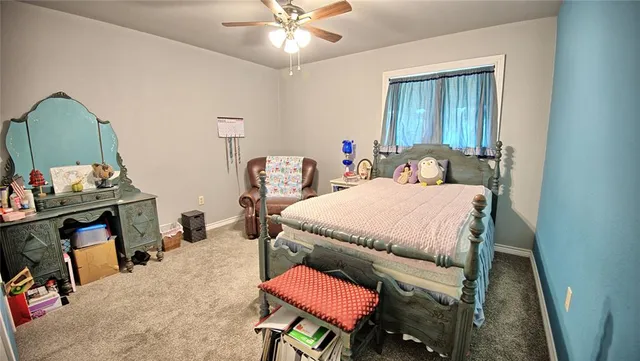 a bedroom with a bed a study table and paintings on the wall