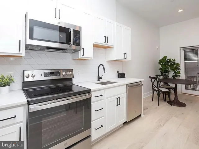 a kitchen with stainless steel appliances a stove microwave and sink