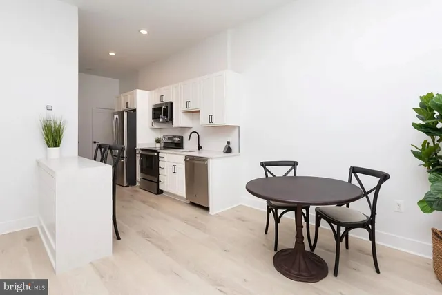 a kitchen with stainless steel appliances a table and chairs in it