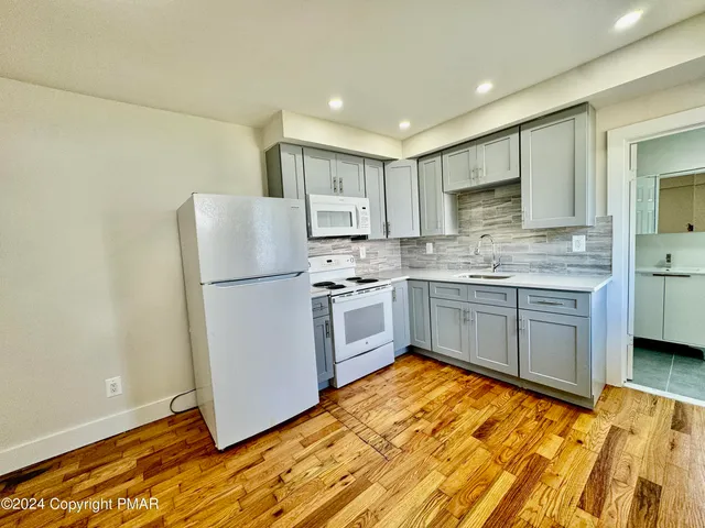 a kitchen with stainless steel appliances granite countertop a refrigerator sink and white cabinets