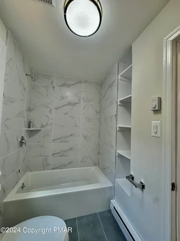 a bathroom with a tub a toilet and a shower