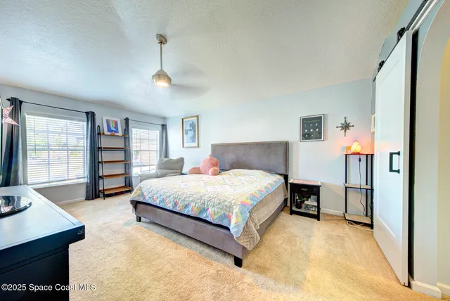 a spacious bedroom with a bed a dresser and a large window