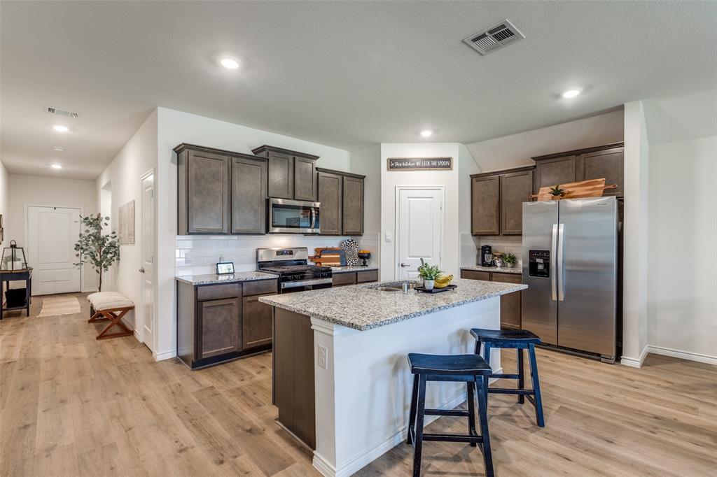 708 Cool Cyn Trail Princeton, TX 75407 - Photo 3 of 28 a kitchen with a refrigerator a stove top oven a sink dishwasher and wooden floor