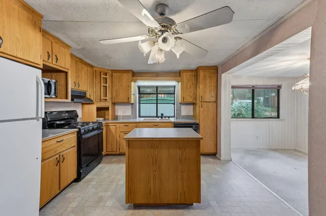 a kitchen with kitchen island granite countertop a stove refrigerator and cabinets