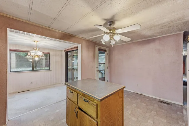 wooden floor in an empty room with a chandelier fan