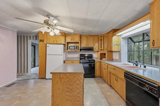 a kitchen with stainless steel appliances a sink a stove a refrigerator cabinets and a large window