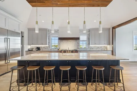 a kitchen with stainless steel appliances granite countertop a table chairs sink and cabinets