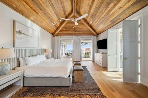 a spacious bedroom with a bed a flat screen tv and balcony view