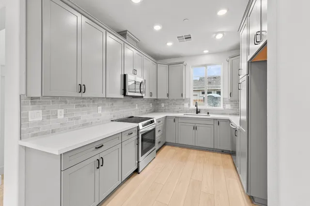 a kitchen with white cabinets appliances and a sink