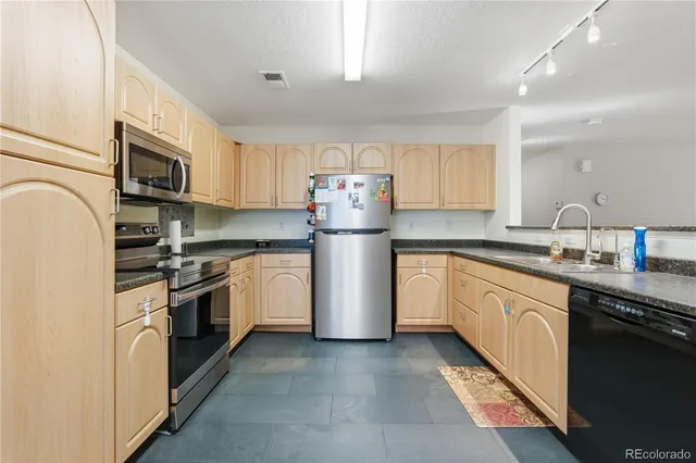 a kitchen with stainless steel appliances granite countertop a refrigerator sink and stove
