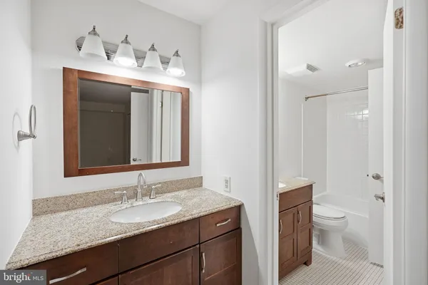 a bathroom with a granite countertop sink toilet mirror and shower