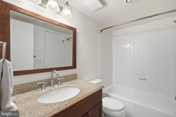 a bathroom with a granite countertop sink toilet a mirror a vanity and shower
