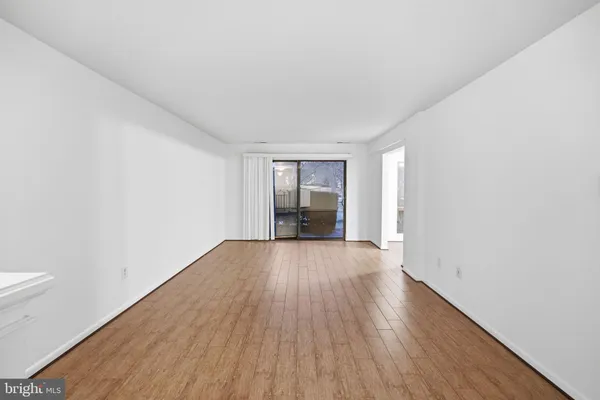 a view of an empty room with wooden floor and cabinets