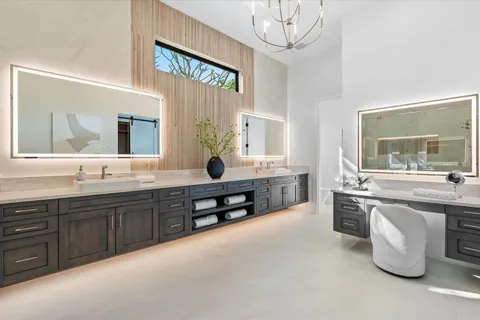 a spacious bathroom with double sink a toilet a window and mirror