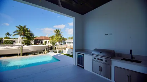 a view of a white house with a yard potted plants and a table chair