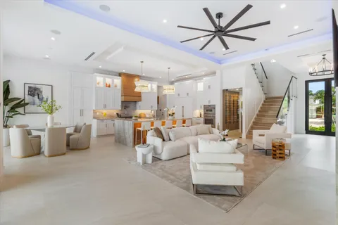 a living room with lots of white furniture and a large window