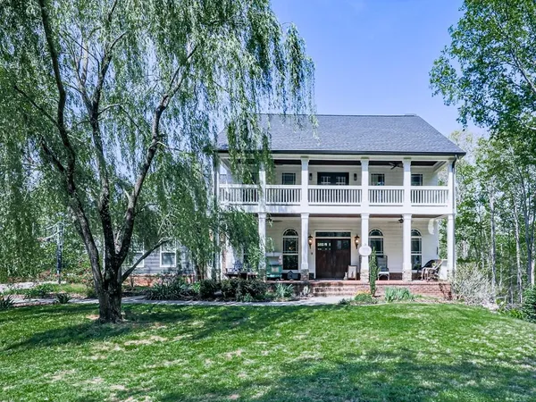 a front view of a house with a garden and trees