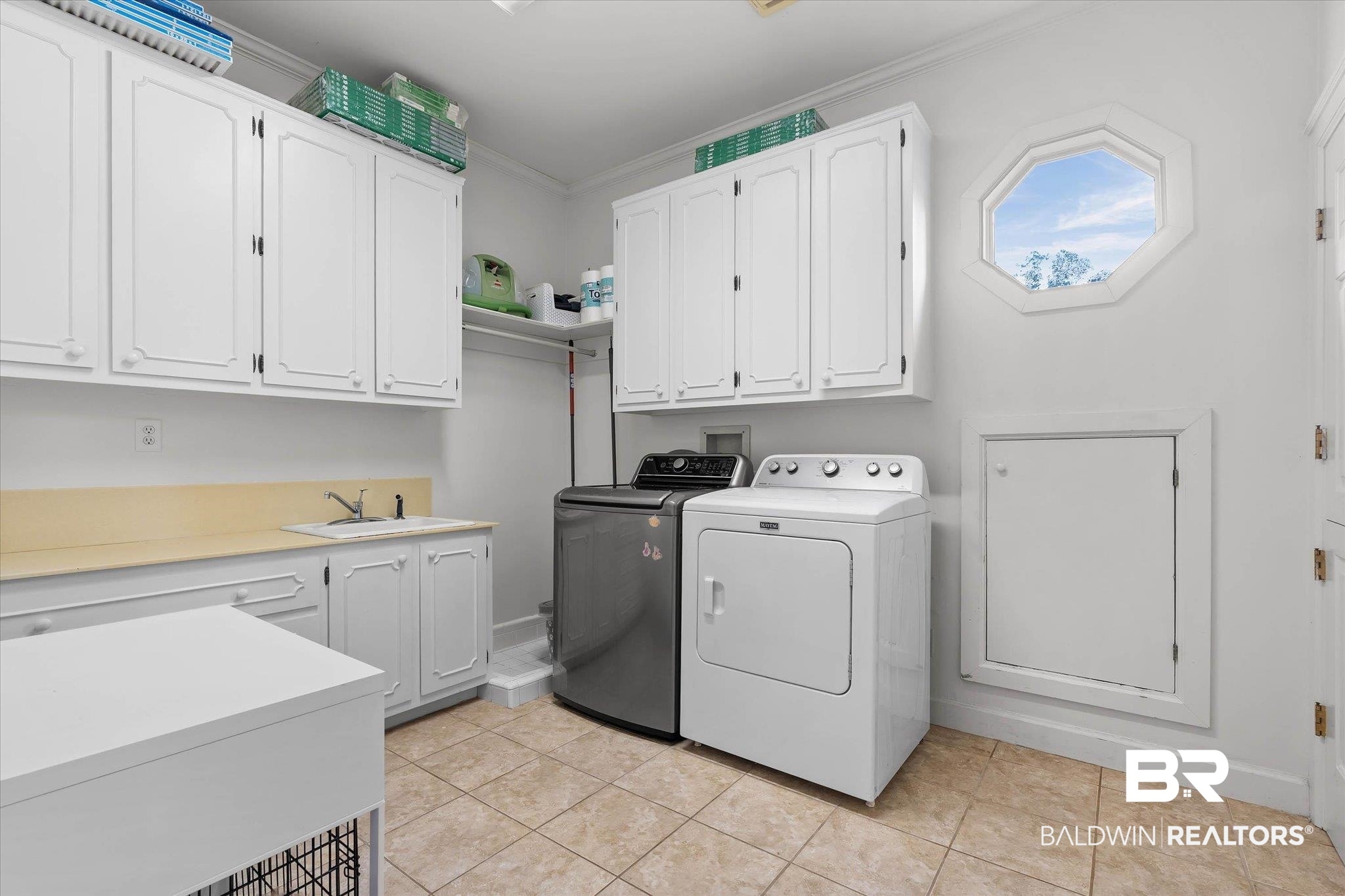 3908 Yester Place Mobile, AL 36608 - Photo 34 of 45 Dedicated utility room featuring extensive white cabinetry, a built-in sink with a countertop, beige tile flooring, and an octagonal window