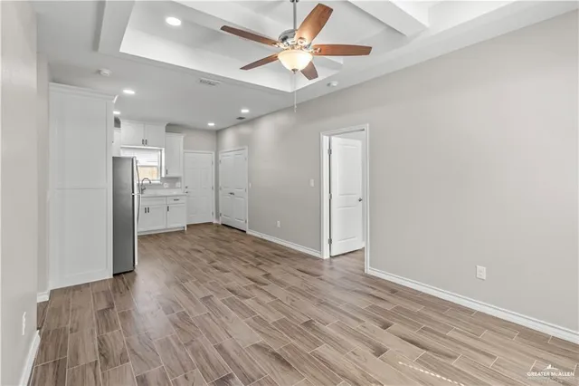 a view of kitchen and empty room with wooden floor