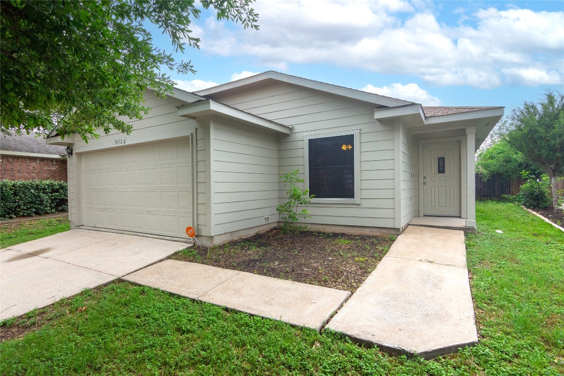 a small white house with a yard and garage
