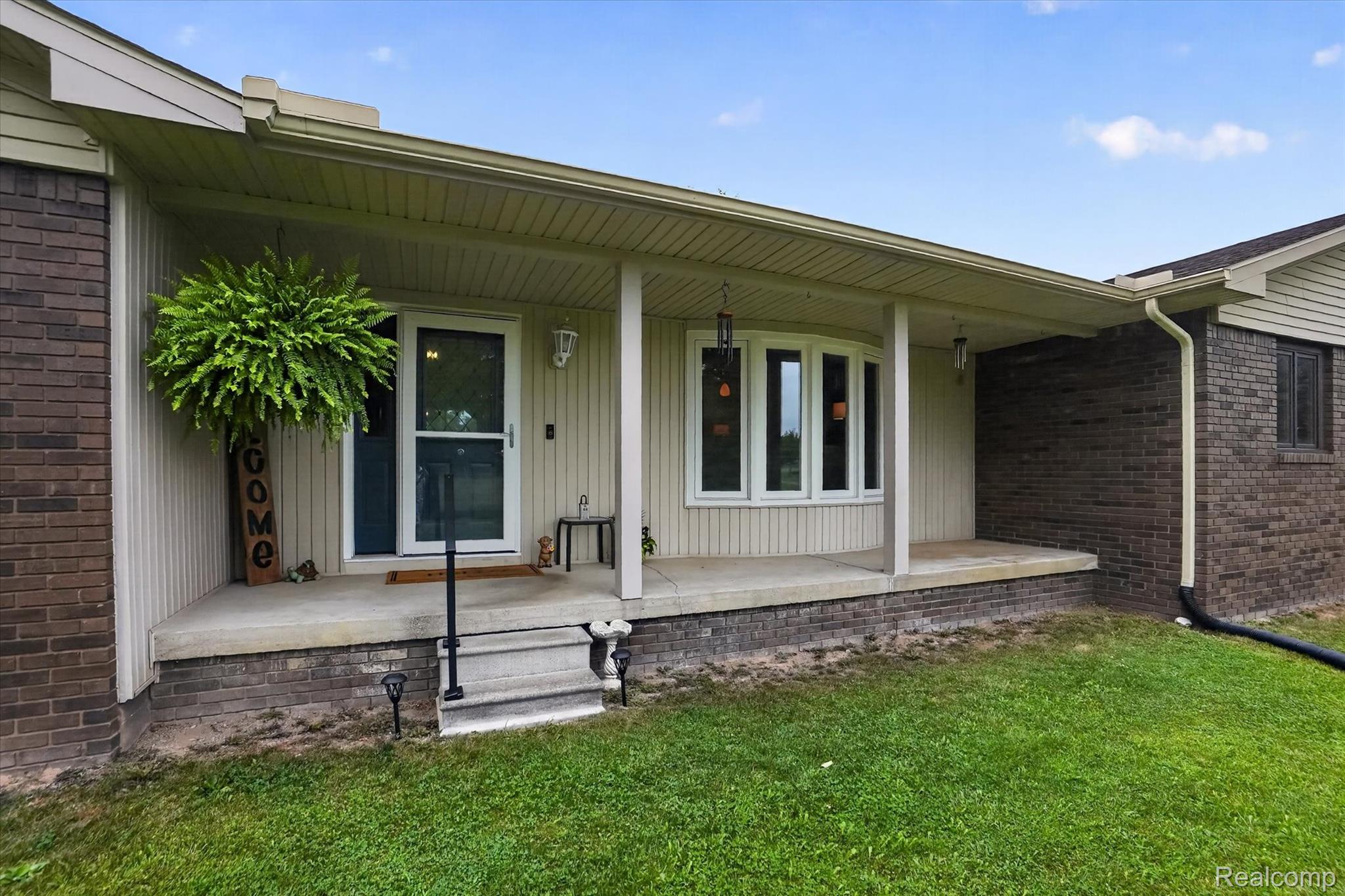 6895 Stow Road Fowlerville, MI 48836 - Photo 2 of 45 Brick and siding exterior featuring a covered porch, bay window, and concrete steps with a black handrail