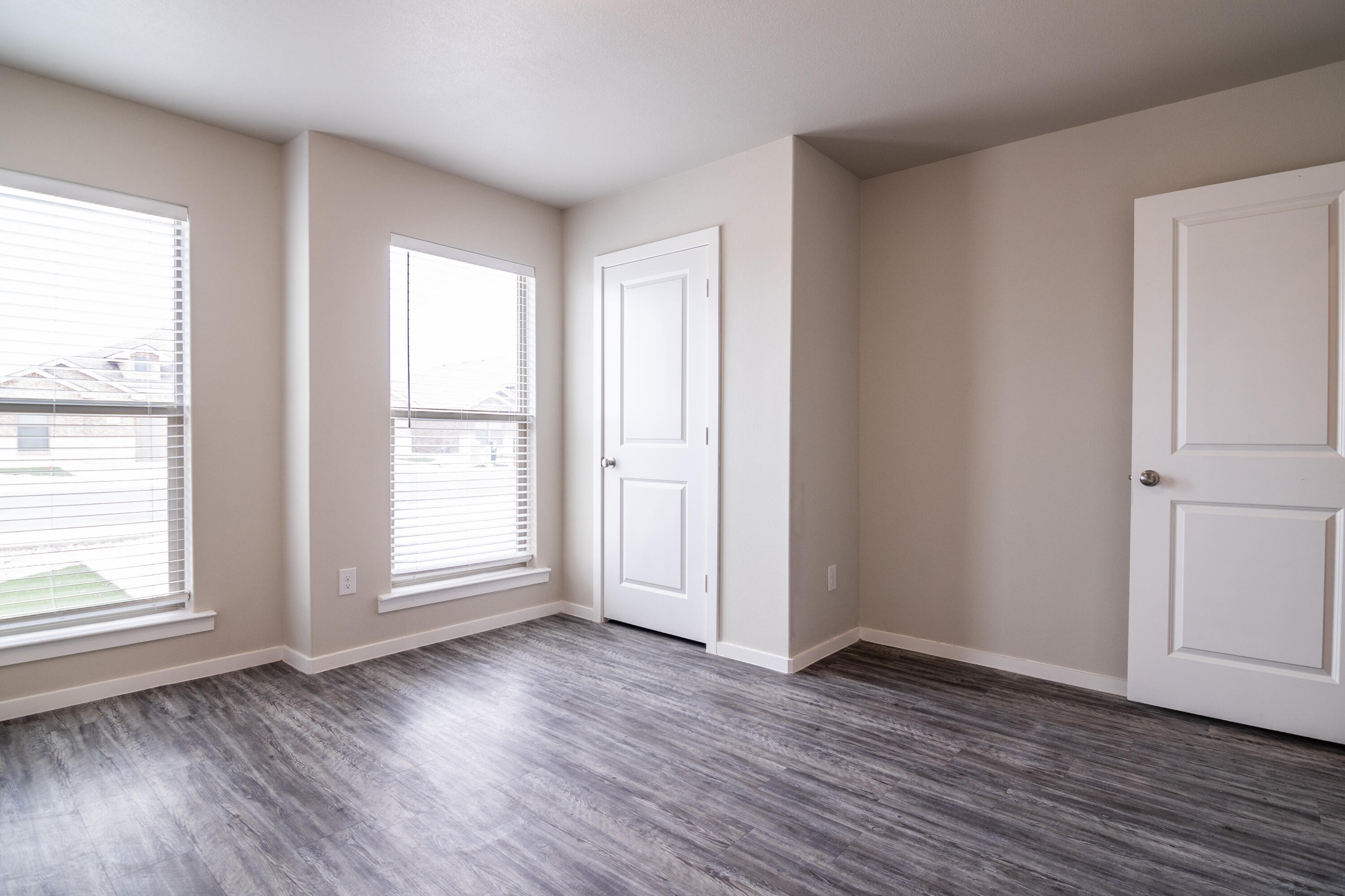 2118 Langford Avenue, Unit B Lubbock, TX 79407 - Photo 6 of 19 an empty room with wooden floor and windows with curtains view