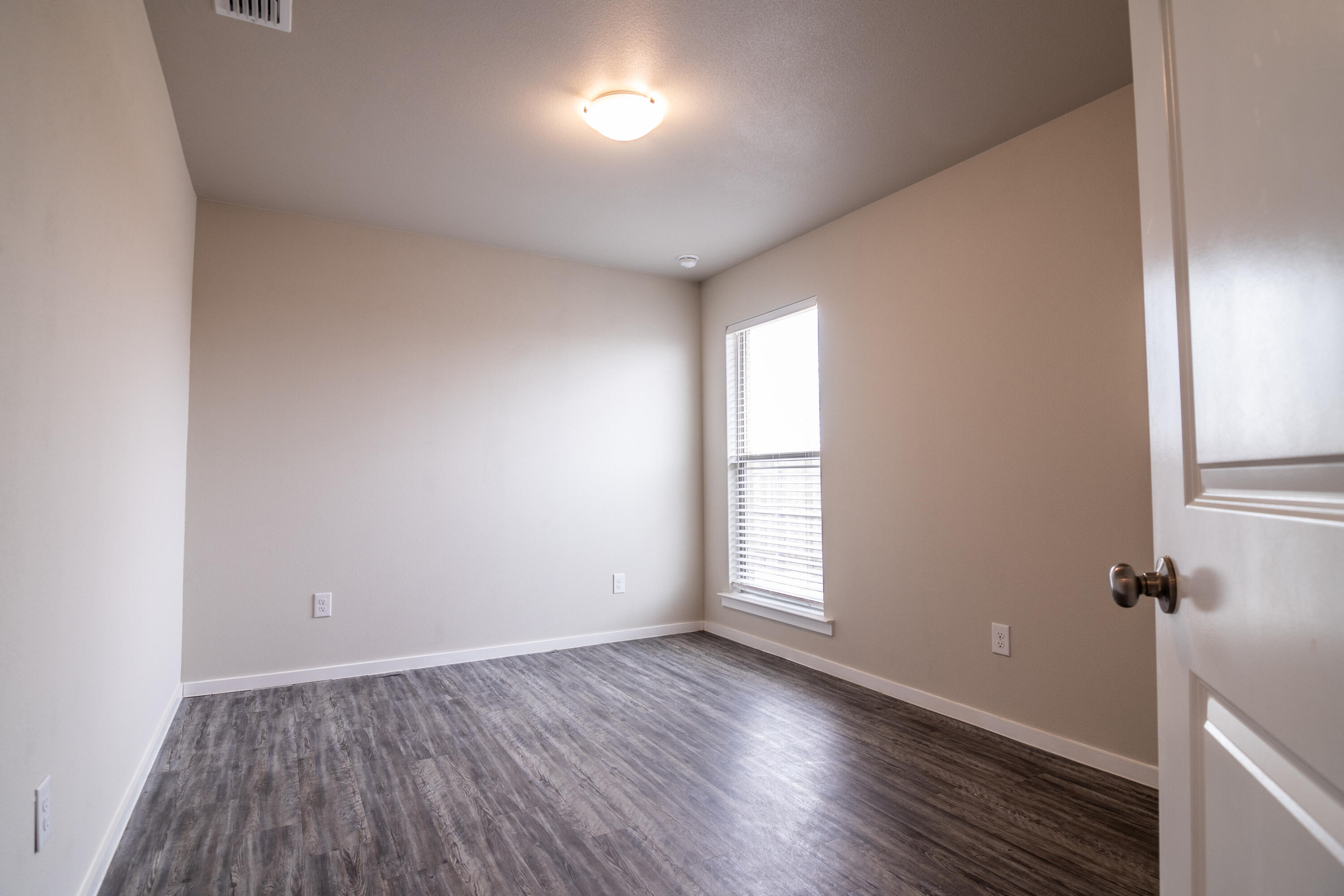 2118 Langford Avenue, Unit B Lubbock, TX 79407 - Photo 7 of 19 an empty room with wooden floor and windows