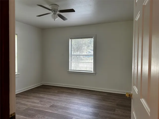 a view of empty room with wooden floor and ceiling fan