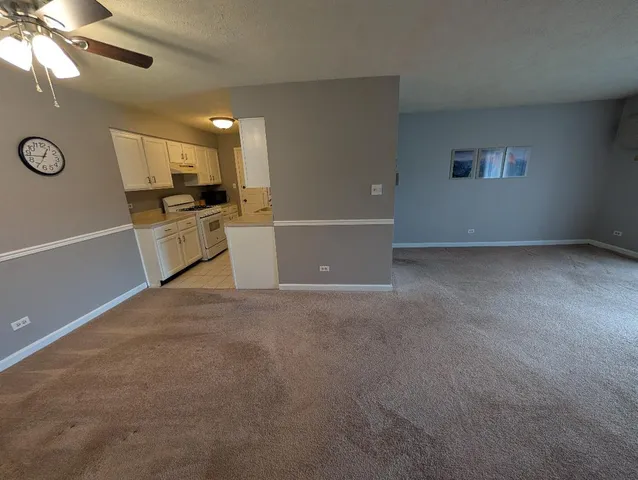 a view of empty room with kitchen appliances and a fan