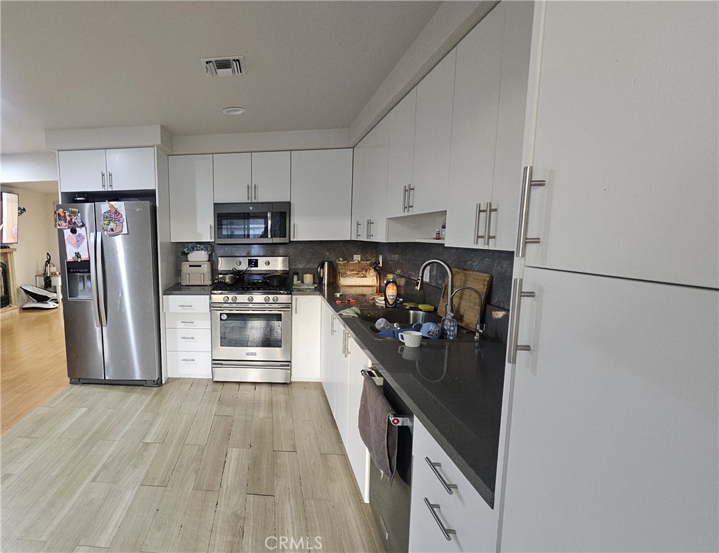 10535 Samoa Avenue Tujunga, CA 91042 - Photo 6 of 25 a kitchen with refrigerator a stove and wooden floor