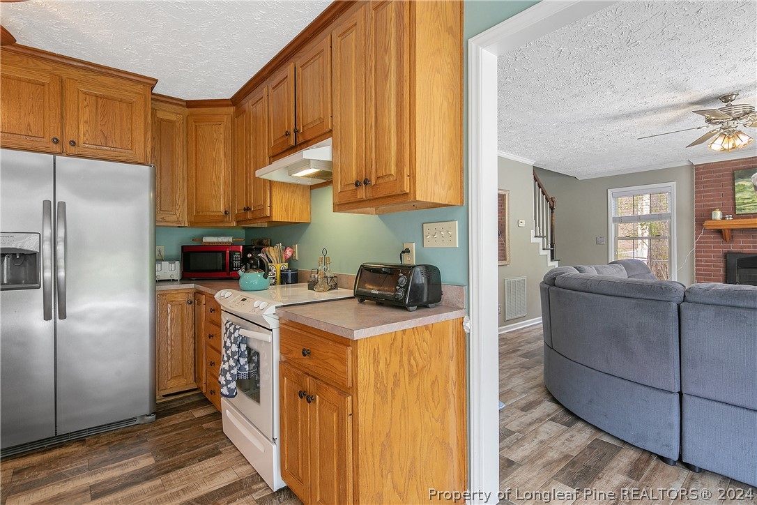 7833 Shuttle Road Fayetteville, NC 28311 - Photo 17 of 46 a kitchen with stainless steel appliances granite countertop a refrigerator a stove and a sink with wooden floor