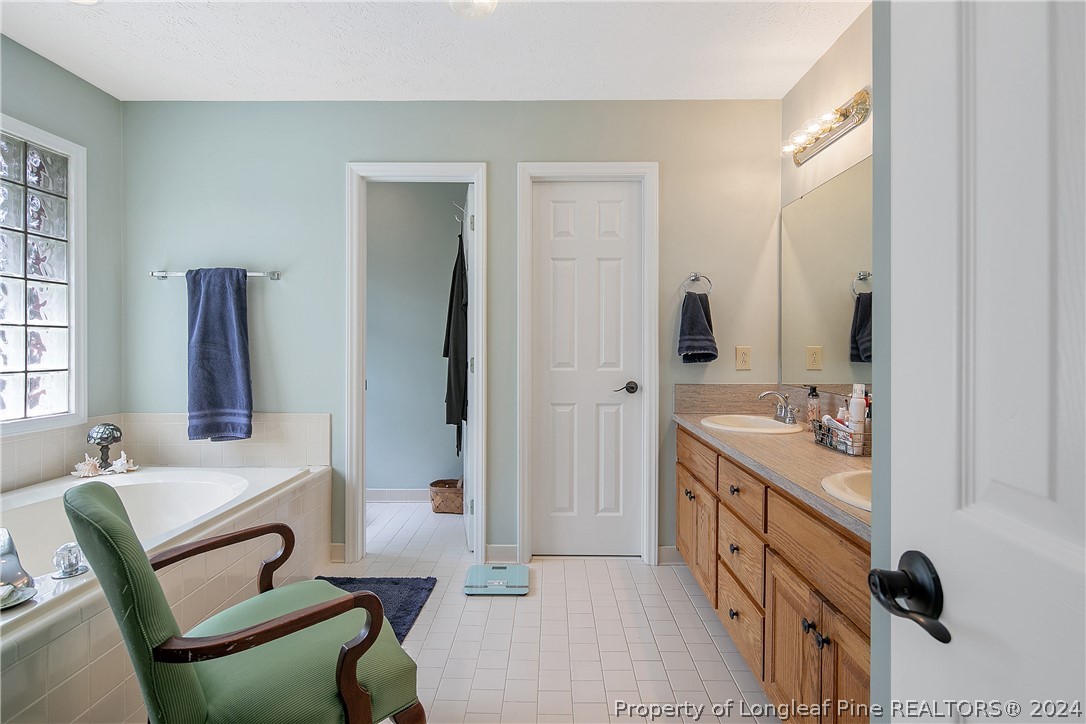 7833 Shuttle Road Fayetteville, NC 28311 - Photo 26 of 46 a bathroom with a double vanity sink a mirror and a bathtub