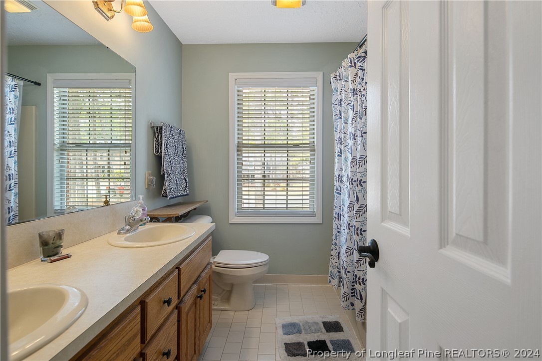 7833 Shuttle Road Fayetteville, NC 28311 - Photo 33 of 46 a bathroom with a sink toilet a mirror and shower