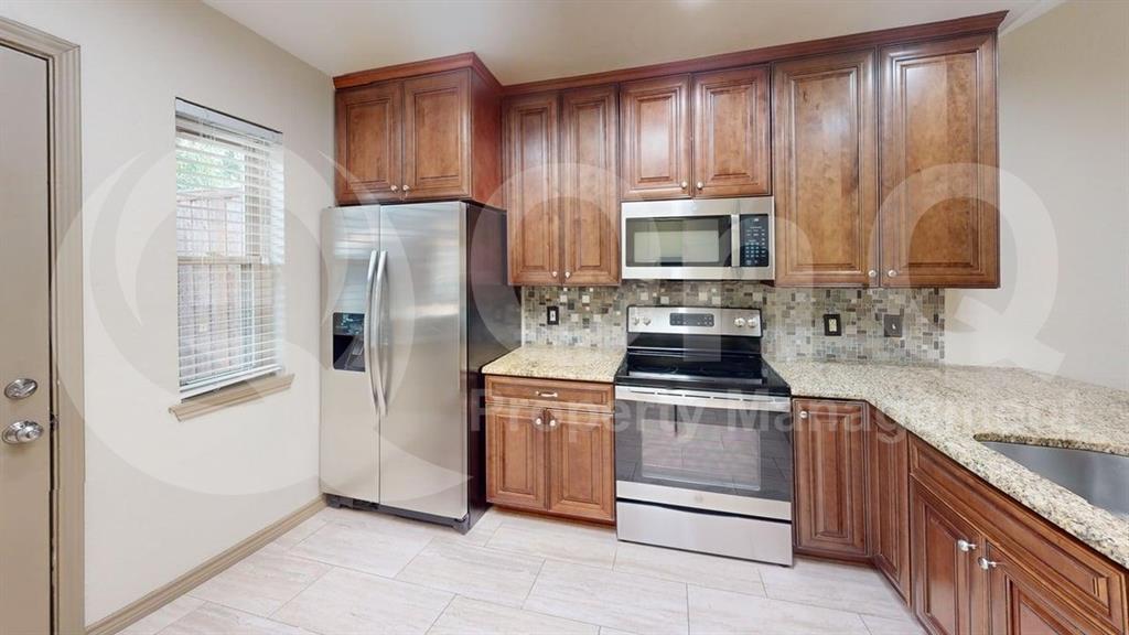 3000 Timothy Lane Euless, TX 76039 - Photo 4 of 19 Kitchen featuring shaker-style wood cabinetry, granite-finish countertops, stainless steel appliances, and a mosaic tile backsplash