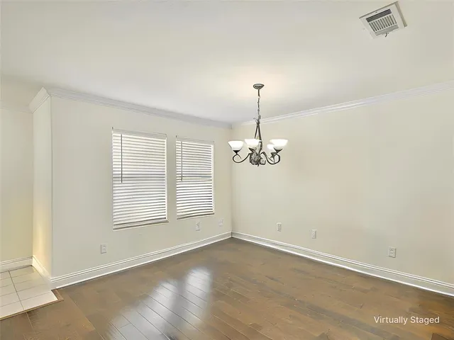 an empty room with chandelier fan and windows