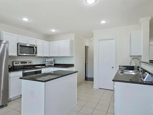 a kitchen with granite countertop white cabinets sink and stainless steel appliances