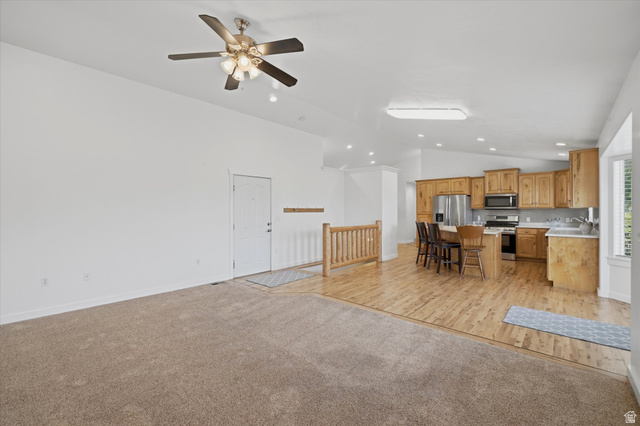 791 East Saddle Road Grantsville, UT 84029 - Photo 17 of 46 Open-concept living space featuring a ceiling fan, light wood-finish flooring, and a kitchen with stainless steel appliances, light wood cabinetry, and a central island