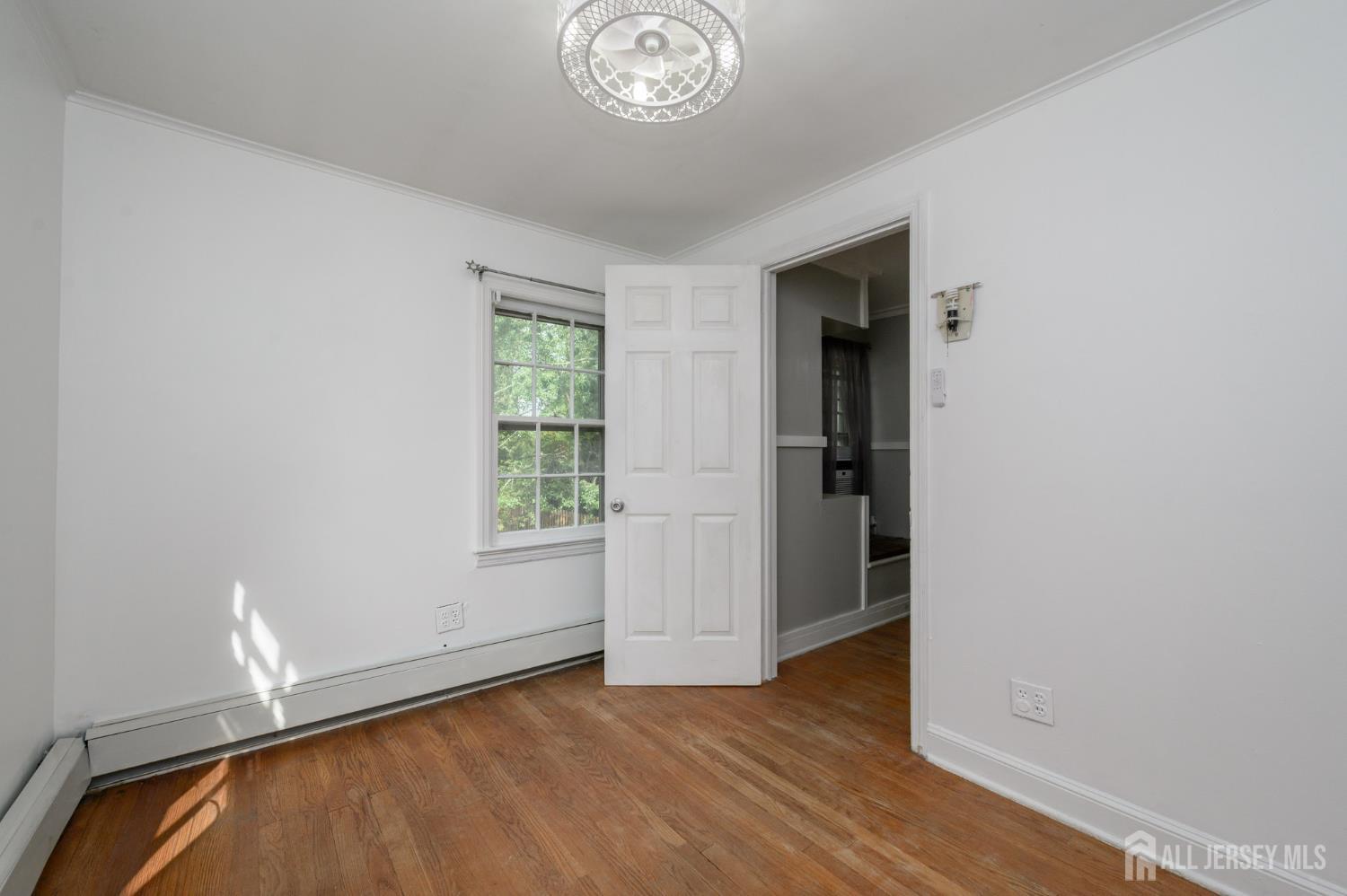 212 Echo Avenue Edison, NJ 08837 - Photo 26 of 42 an empty room with wooden floor cabinet and windows