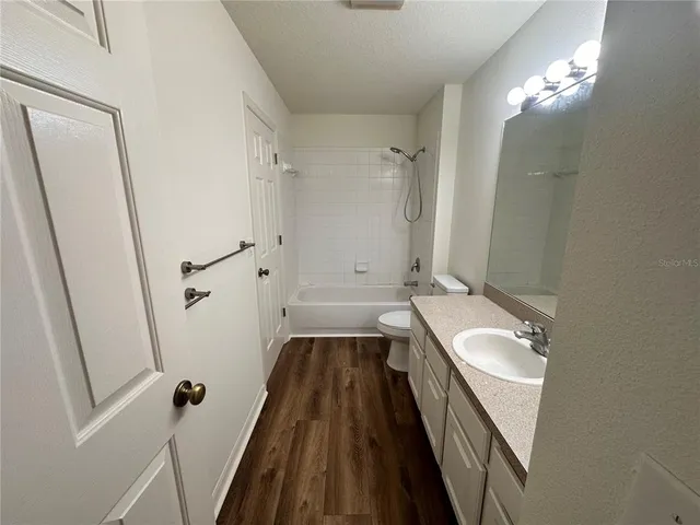 a bathroom with a tub a sink and wooden floor