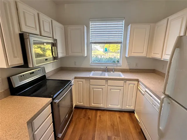 a kitchen with granite countertop cabinets stainless steel appliances a sink and a window