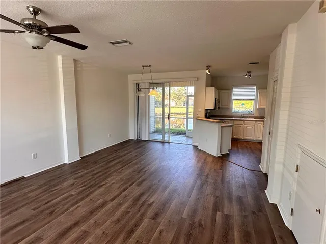 a view of a kitchen and an empty room with a window