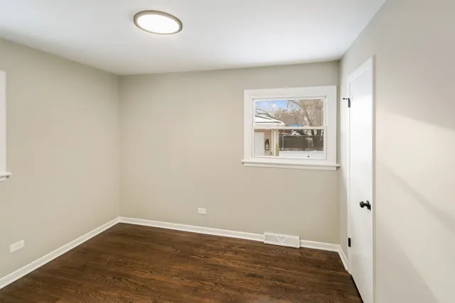an empty room with wooden floor and window