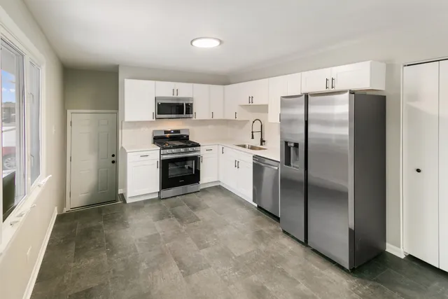 a kitchen with stainless steel appliances granite countertop a refrigerator a stove and a sink